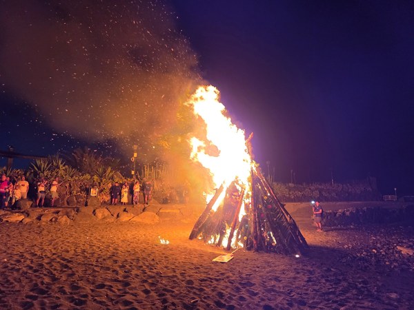 Feu de la Saint-Jean Grand bûcher en flammes sur la plage pendant la nuit de la Saint-Jean à Tenerife, entouré de spectateurs.